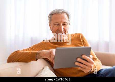 Relaxed senior man using digital tablet at home Stock Photo