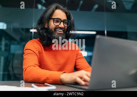 Positive hard-working indian man IT professional working on laptop Stock Photo