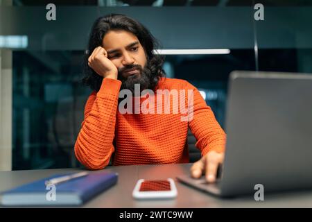 Tired millennial eastern man startuper working late at night Stock Photo