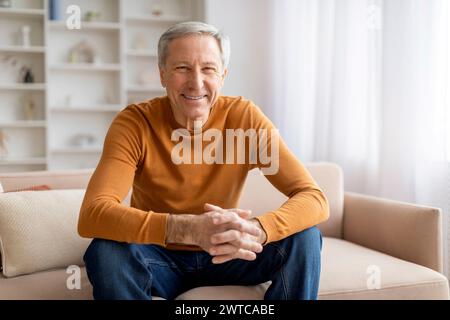 Positive senior man sitting on couch at home Stock Photo