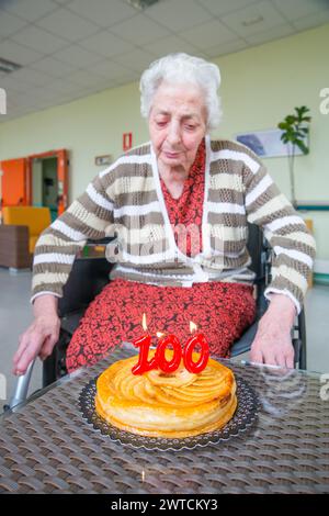 Old woman in a nursing home, on her one hundred birthday, blowing birthday's candles. Stock Photo