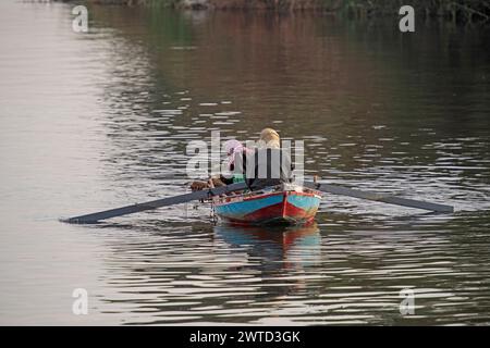 Traditional egyptian bedouin fisherman in rowing boat on river Nile fishing by riverbank Stock Photo