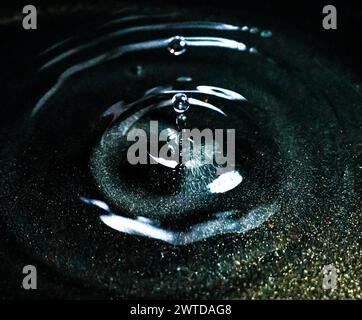 Light reflects on liquid in black bowl creating ripples Stock Photo