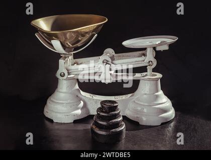 Old obsolete manual weighing scales and Iron Brass Tray with set of cast iron weights. Classic weight scale Isolated on dark background, Antique balan Stock Photo