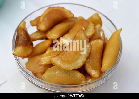 A bowl of qatayef dumplings stuffed and filled with nuts and shredded coconut fried in deep oil and soaked with sugar syrup, Arabic dessert folded pan Stock Photo