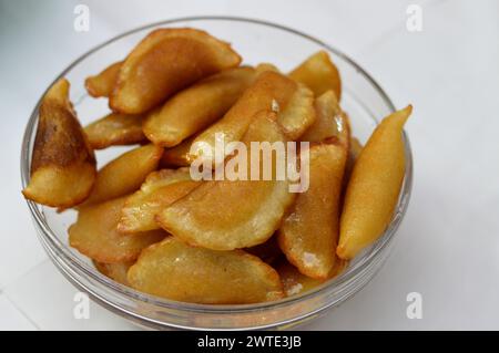 A bowl of qatayef dumplings stuffed and filled with nuts and shredded coconut fried in deep oil and soaked with sugar syrup, Arabic dessert folded pan Stock Photo