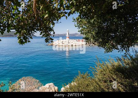 View over white lighthouse through the tree leaves in Kas marina, Turkey Stock Photo