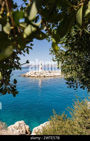 View over white lighthouse through the tree leaves in Kas marina, Turkey Stock Photo