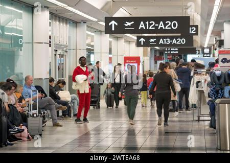 TORONTO, CANADA - 03 10 2024: A crowded Terminal 3 hall at Toronto Pearson International Airport with travelers walking and waiting to board their Stock Photo
