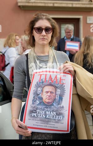 March 17, 2024, Rome, Italy: A woman holds up a sign depicting the Time cover with Navalny's portrait and the headline 'The man Putin killed' among people queuing for the Russian presidential elections in Rome. A long queue of people to reach the Russian embassy in Rome for the Russian presidential elections. The turnout of the first voters began shortly after 8am, but after 11.30am attendance registered a rapid increase. Navalny's latest appeal called for mass attendance at polling stations at 12pm on the third and final day of open polls for the presidential elections. In Italy it was possib Stock Photo