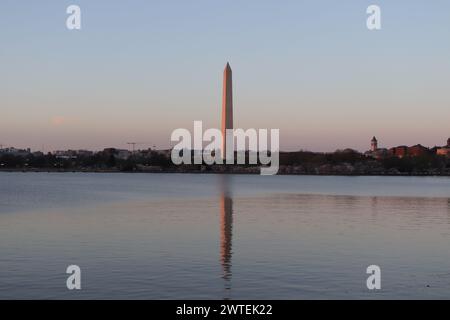 Cherry blossom trees at sunset along the Tidal Basin with the Washington Monument reflected in the water, Washington, DC, USA. Stock Photo