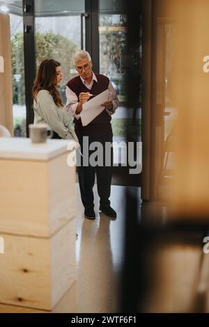 Senior executive discussing document with younger colleague in modern office. Stock Photo