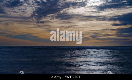 Sunset cloudy sky over the coast line. Stock Photo