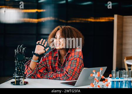 A Black teenage student tests a robotic arm on a classroom table exploring and learning subjects of Stock Photo