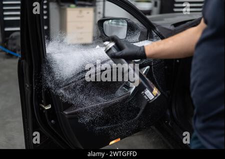 A man sprays cleaning foam on the interior of a car. Stock Photo