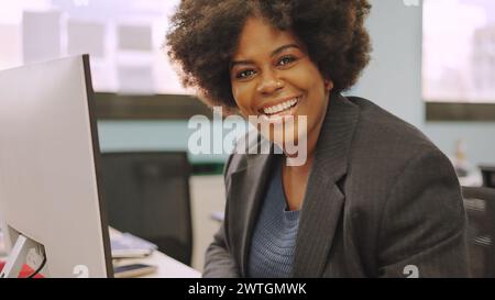 African american coworker smiling at camera sitting in the office Stock Photo