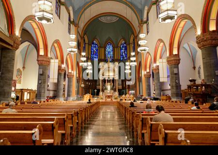 St. Paul the Apostle Church NYC, interior of a church with pews and colourful stained glass windows under a vaulted ceiling, Manhattan, New York Stock Photo
