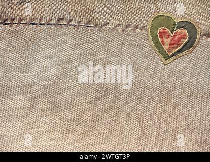 Two pieces of old burlap sewn together with thread and fabric heart. Horizontal background with rustic bag texture and Valentine's day decor in patchw Stock Photo