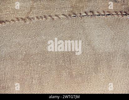 Two pieces of old burlap sewn together with thread. Horizontal background with rustic bag texture Stock Photo