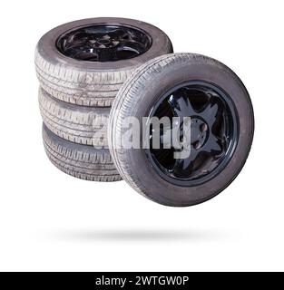 Automobile composition made up stack of tires and wheel with shiny black disc in the foreground against the background of cars in a car service before Stock Photo