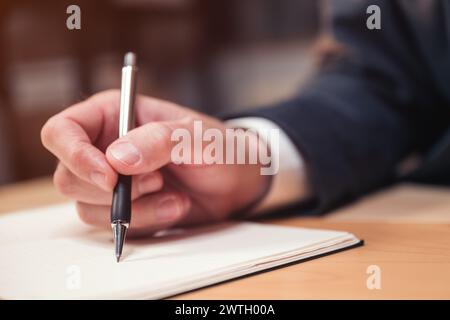 Closeup of male hand with pen businessman writing notes and remarks in notebook, selective focus Stock Photo