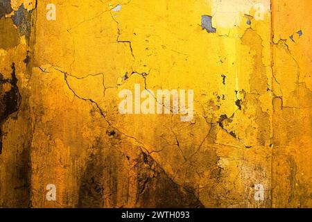 Vibrant yellow wall of old ruined house with cracks and stains as background and texture Stock Photo