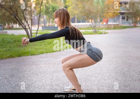 Side view active and fit female athlete doing squats exercise outdoors. Stock Photo