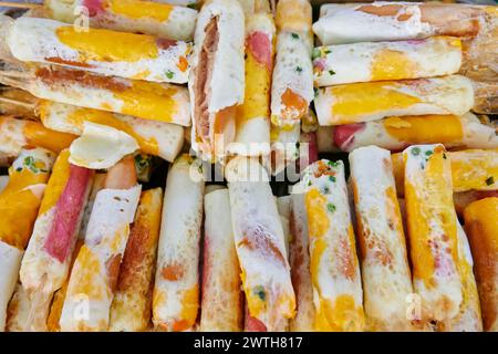 Skewer fried egg wrapped hot dog at street market Stock Photo