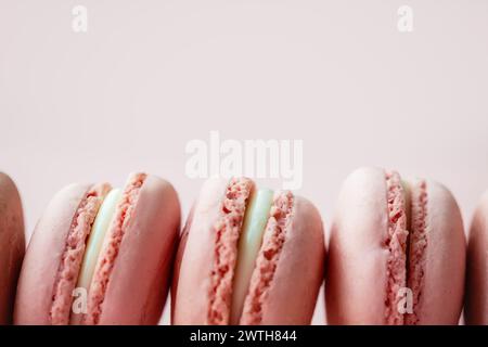 Close-up of macarons in a row on a pale pink surface Stock Photo