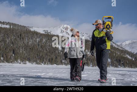 Man and woman walking on a frozen lake in Colorado Stock Photo