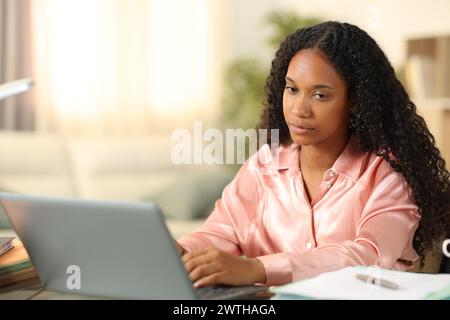 Distracted black tele worker looking away working online at home Stock Photo