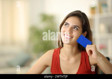 Happy woman dreaming and showing blank credit card at home Stock Photo