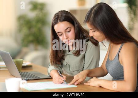 Tele worker explaining where to sign contract to her colleague at home Stock Photo