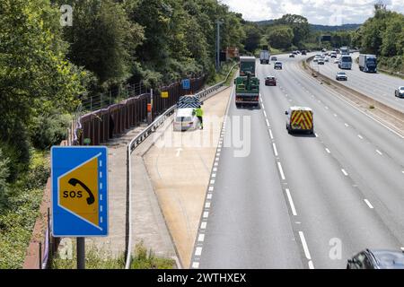 Car rescue worker stands close to traffic in refuge on smart motorway Stock Photo