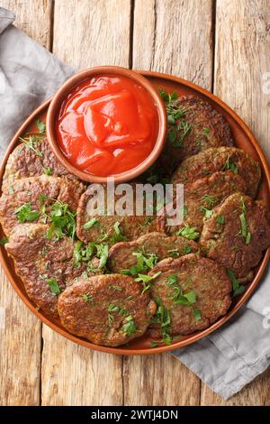 Delicious beef liver patties served with tomato sauce close-up in a plate on the table. Vertical top view from above Stock Photo