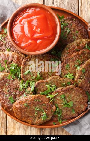 Beef liver cutlets served with tomato sauce close-up in a plate on the table. Vertical top view from above Stock Photo