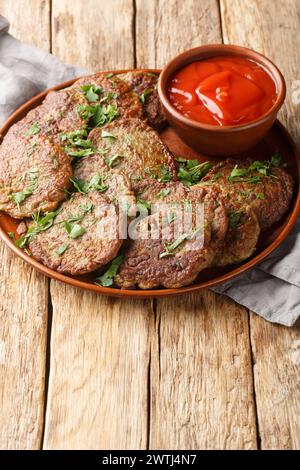 Beef liver cutlets served with tomato sauce close-up in a plate on the table. Vertical Stock Photo
