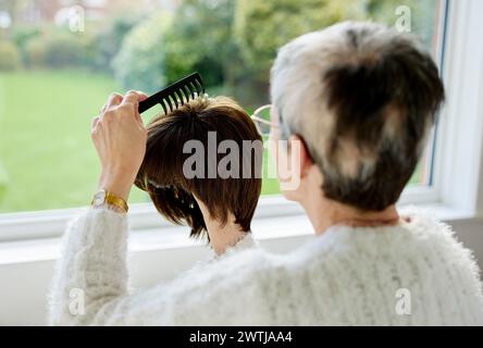 Woman with Alopecia combing a wig Stock Photo