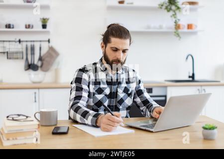 Caucasian man wearing checkered shirt writing on document. Stock Photo