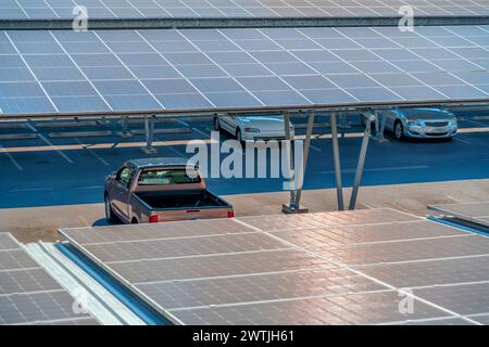 Solar panels canopy roof shelter installed over parking lot with parked cars for effective generation of clean energy, aerial top view. Stock Photo