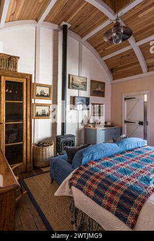 Tartan blanket and woodburning stove with blue sofa in luxury hotel in Ardfin on the Isle of Jura, Inner Hebrides, Scotland, UK Stock Photo