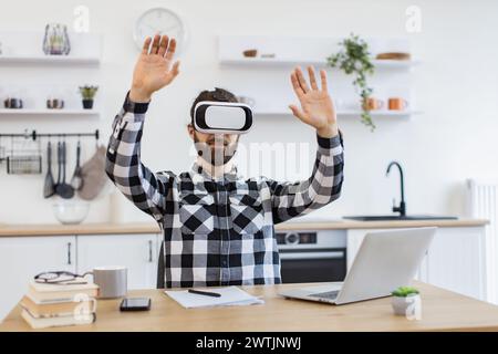 Caucasian worker testing VR headset while sitting at wooden table. Stock Photo