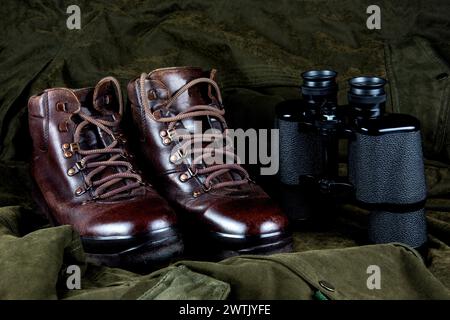 Binoculars and old hiking boots on an outdoor field coat Stock Photo