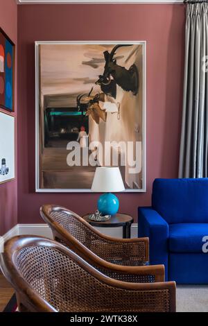 Modern artwork with blue sof and pair of wicker armchairs in Irish home in Greystones, County Wicklow, Ireland Stock Photo