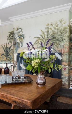 Elegant cut flowers on wooden table with tropical palm tree wall decor in Irish home in Greystones, County Wicklow, Ireland Stock Photo