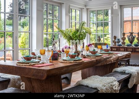 Sheepskin throws on bench seating at dining table in Irish conservatory, Greystones, County Wicklow, Ireland Stock Photo