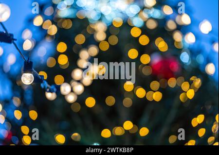 Christmas tree covered snow with yellow garlands lights and bokeh copy space Stock Photo