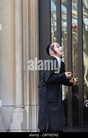 An orthodox Jewish lad practices his juggling on the steps of his school and during recess. In Brooklyn, New York. Stock Photo