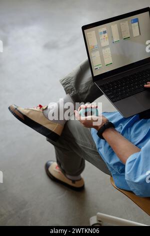 Vertical closeup of unrecognizable young hand holding hand expander while using laptop minimal copy space Stock Photo
