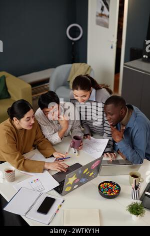 Vertical high angle view at diverse coworkers working together at meeting table in office Stock Photo